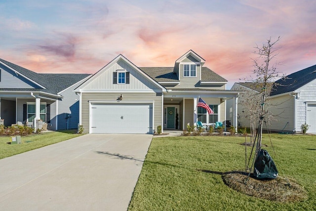 view of front of property featuring covered porch, a yard, and a garage