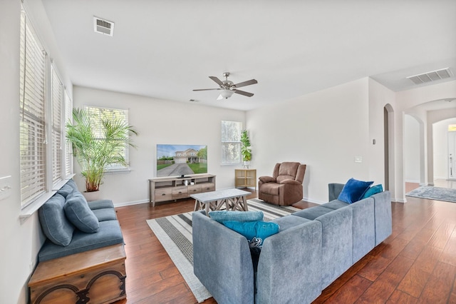 living area featuring arched walkways, dark wood finished floors, ceiling fan, and baseboards