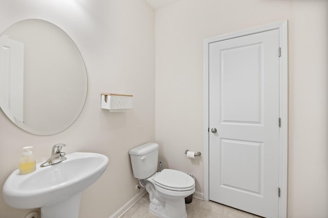 bathroom featuring a sink, baseboards, toilet, and tile patterned flooring