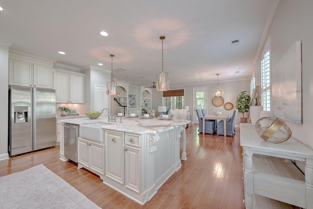 2036 Kings Gate Ln, Mount Pleasant, SC 29466 - kitchen featuring stainless steel appliances, crown molding, white cabinetry, light stone counters, and a kitchen island with sink