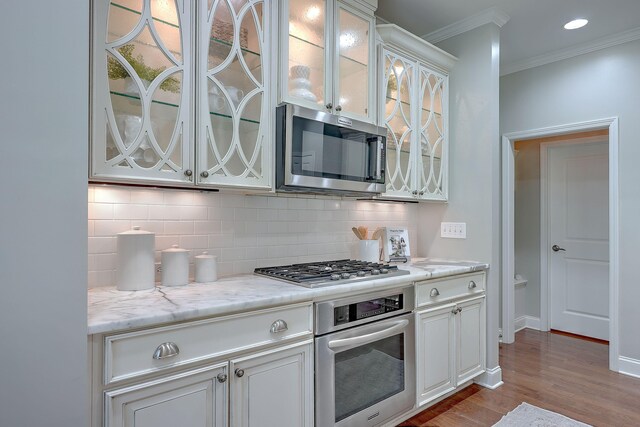 2036 Kings Gate Ln, Mount Pleasant, SC 29466 - kitchen featuring appliances with stainless steel finishes, crown molding, tasteful backsplash, wood finished floors, and glass insert cabinets