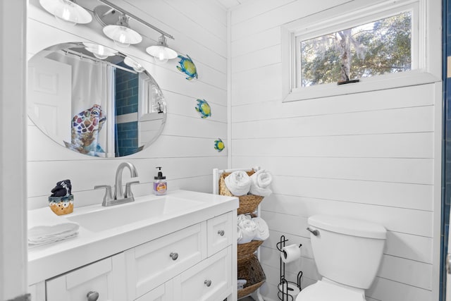 bathroom with vanity, wooden walls, and toilet