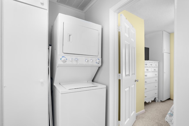 clothes washing area featuring stacked washer / dryer, light carpet, and a textured ceiling