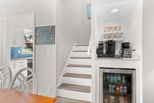 staircase with hardwood / wood-style floors and beverage cooler