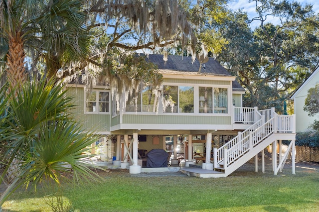 rear view of property featuring a wooden deck, a yard, a patio area, and a sunroom