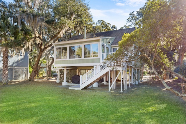 back of property with a sunroom and a lawn