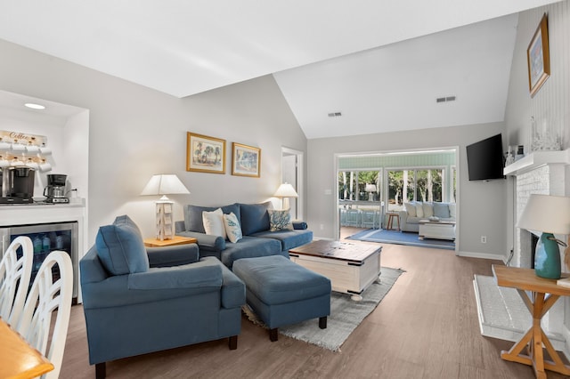 living room featuring wood-type flooring, a fireplace, and high vaulted ceiling