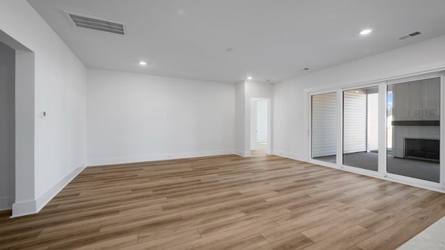 empty room featuring light wood-type flooring, visible vents, and a fireplace