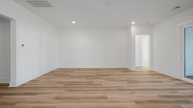 spare room with light wood-type flooring, visible vents, and baseboards