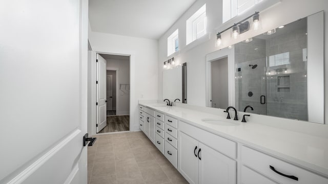 bathroom featuring double vanity, a stall shower, tile patterned flooring, and a sink