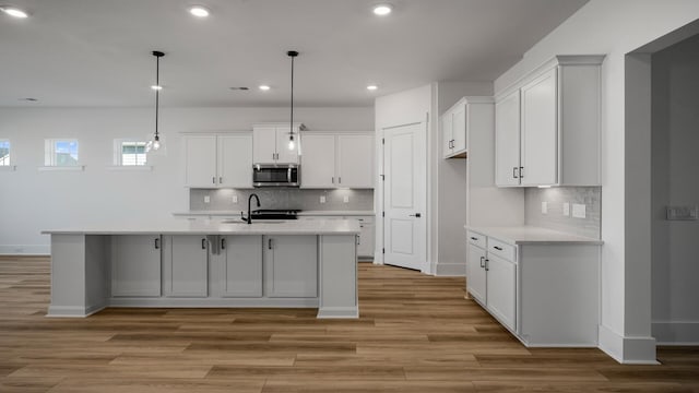 kitchen with light countertops, stainless steel microwave, and white cabinets