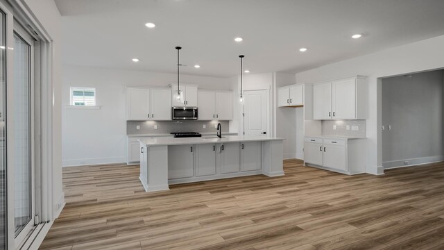 kitchen with light countertops, stainless steel microwave, a sink, and white cabinetry