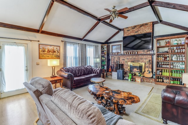 living room with ceiling fan, a wealth of natural light, a fireplace, and lofted ceiling with beams