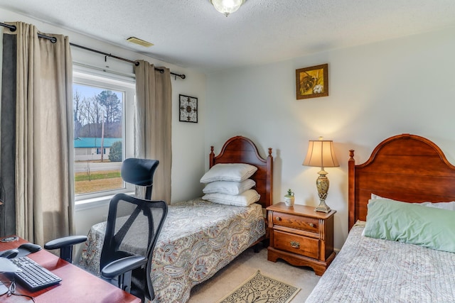 bedroom featuring light colored carpet and a textured ceiling