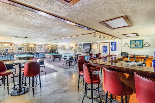 interior space with rail lighting, billiards, concrete floors, and a textured ceiling