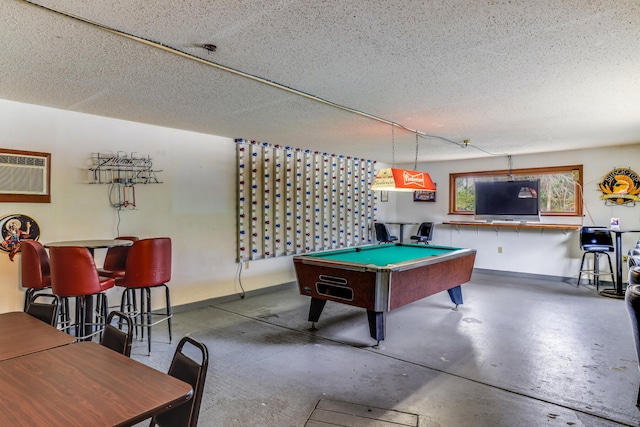 game room with a textured ceiling, billiards, a wall unit AC, and concrete flooring