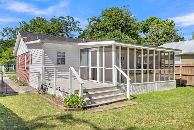 rear view of property featuring a yard and a sunroom