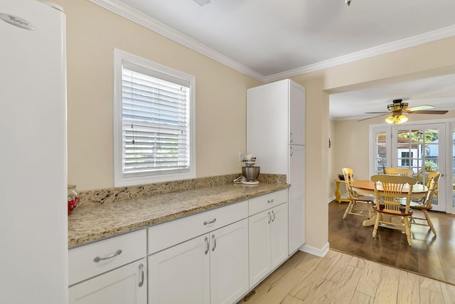 kitchen featuring light stone counters, ceiling fan, light wood-type flooring, and white cabinetry