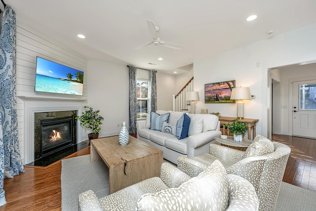 living area with a premium fireplace, stairway, a healthy amount of sunlight, and wood-type flooring