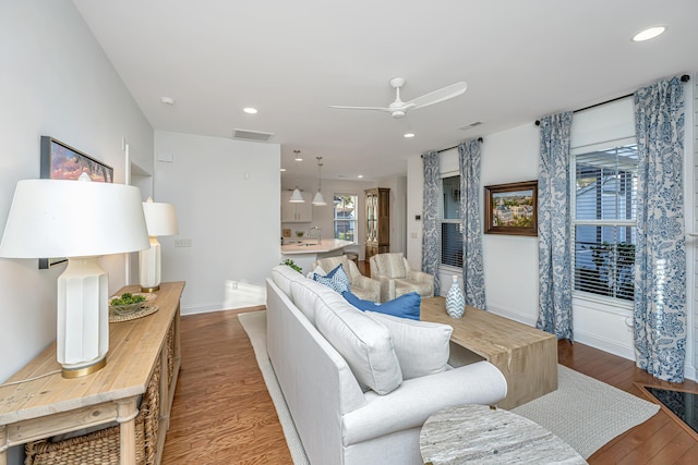 living room with a ceiling fan, visible vents, wood finished floors, baseboards, and recessed lighting