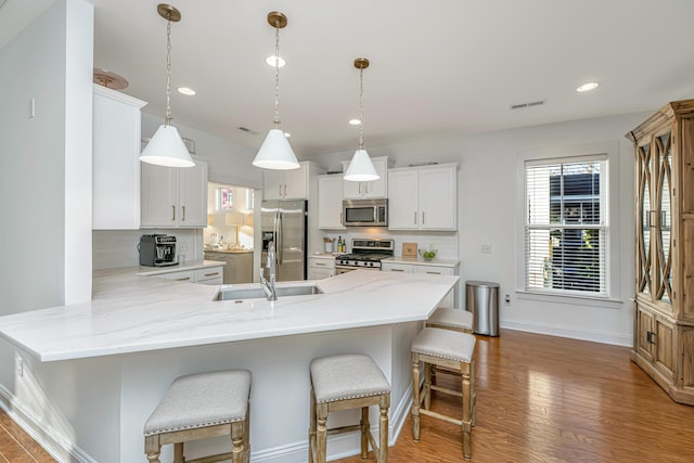 kitchen with backsplash, a breakfast bar, light wood-style flooring, a peninsula, and stainless steel appliances