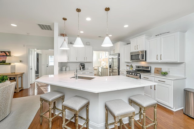 kitchen with a sink, visible vents, appliances with stainless steel finishes, and a breakfast bar area