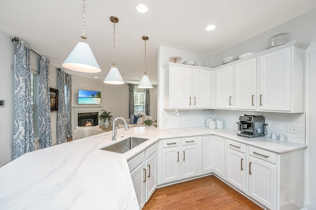 kitchen with a sink, decorative backsplash, a glass covered fireplace, and white cabinets