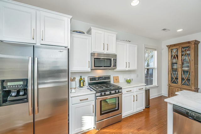 kitchen with visible vents, backsplash, appliances with stainless steel finishes, and light countertops