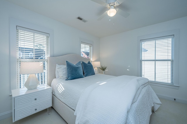 bedroom featuring light carpet, visible vents, a ceiling fan, and baseboards