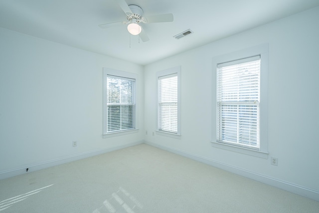 spare room featuring visible vents, light carpet, baseboards, and ceiling fan