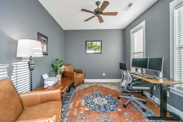 home office with a wealth of natural light, visible vents, baseboards, and wood finished floors