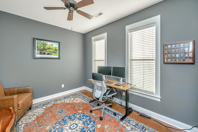 office space featuring wood finished floors, visible vents, baseboards, and ceiling fan