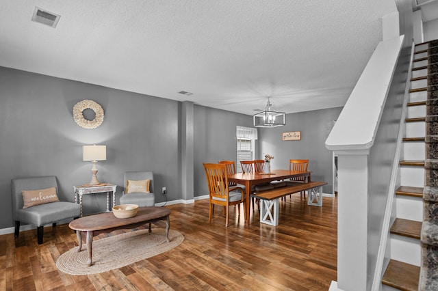 dining space featuring wood-type flooring, an inviting chandelier, and a textured ceiling