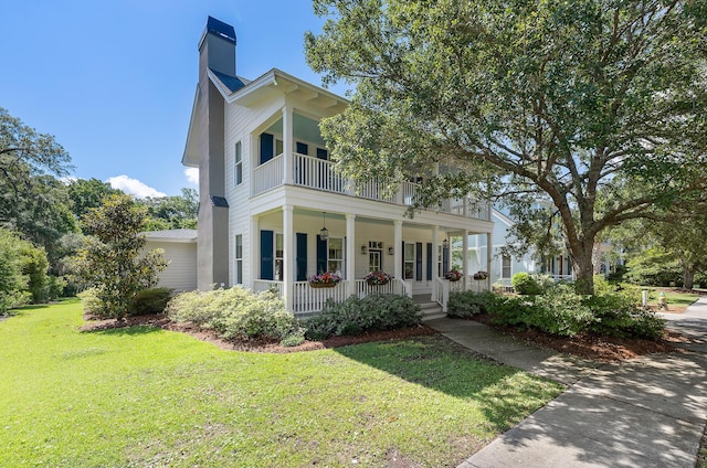 view of front of home featuring a balcony, a porch, a front lawn, and a chimney