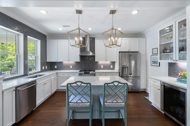 kitchen with stainless steel appliances, beverage cooler, wall chimney range hood, a chandelier, and a sink
