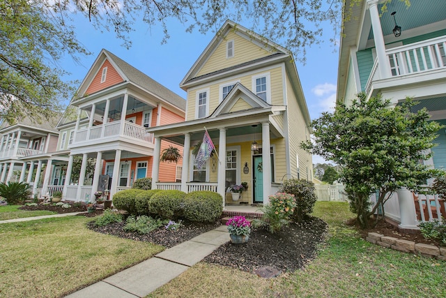 view of front of home featuring a porch, a front yard, fence, and a balcony