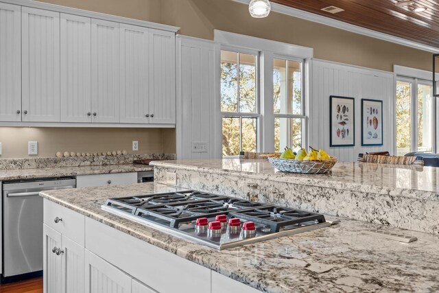 kitchen with light stone counters, appliances with stainless steel finishes, white cabinets, and crown molding