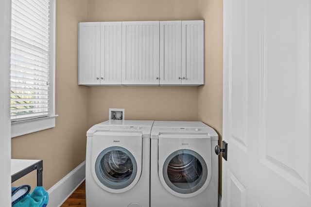 washroom with baseboards, cabinet space, and washing machine and clothes dryer