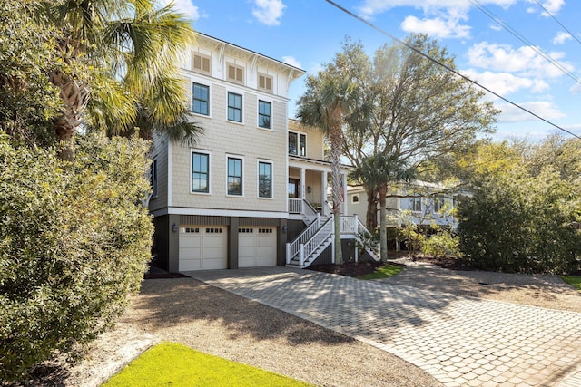 view of front of property featuring stairway, covered porch, decorative driveway, and a garage