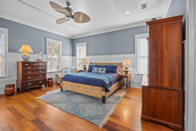 bedroom featuring visible vents, wainscoting, crown molding, and wood finished floors