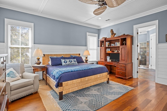 bedroom featuring wainscoting, crown molding, and light wood-style flooring