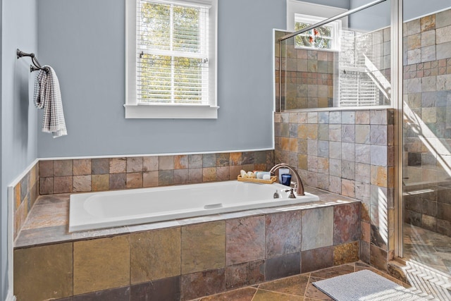 bathroom featuring a garden tub, stone tile floors, and a shower stall