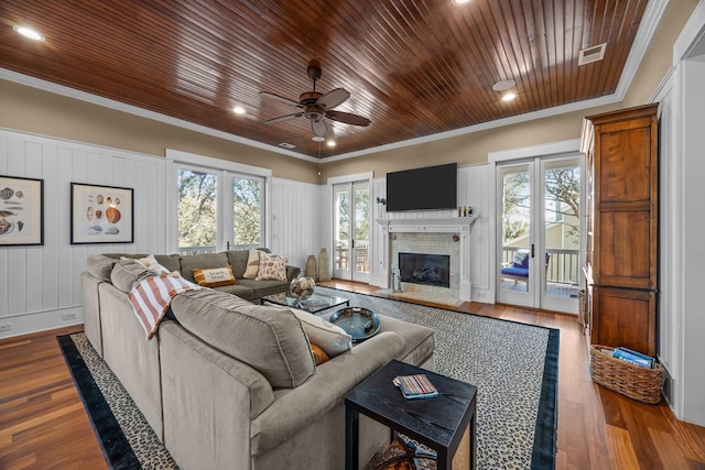 living area with visible vents, a brick fireplace, wood ceiling, ornamental molding, and wood finished floors