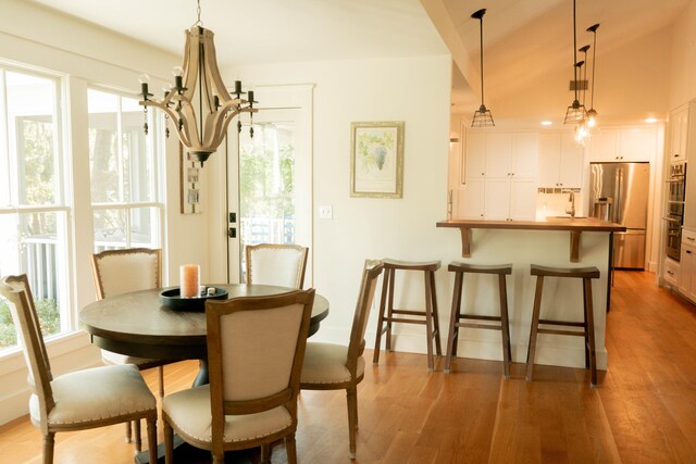 dining space with sink, wood-type flooring, and a chandelier