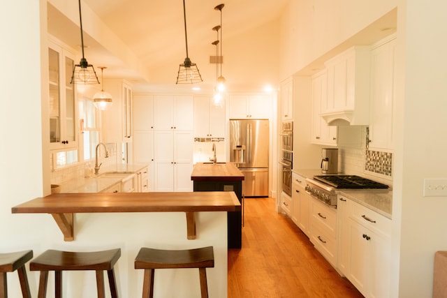 kitchen featuring white cabinetry, stainless steel appliances, sink, and pendant lighting