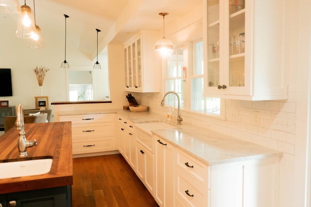 kitchen with light stone counters, decorative light fixtures, and white cabinets