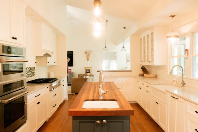 kitchen with white cabinetry, wooden counters, sink, and pendant lighting