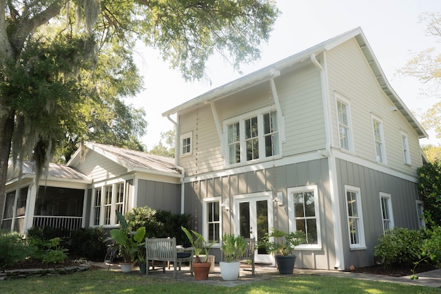 back of house featuring a yard, a sunroom, and french doors