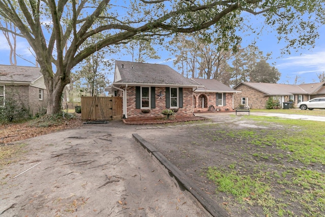 view of front of home featuring a gate, brick siding, and driveway