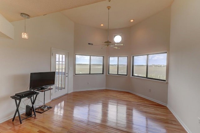 living room featuring a healthy amount of sunlight, light hardwood / wood-style flooring, and a towering ceiling